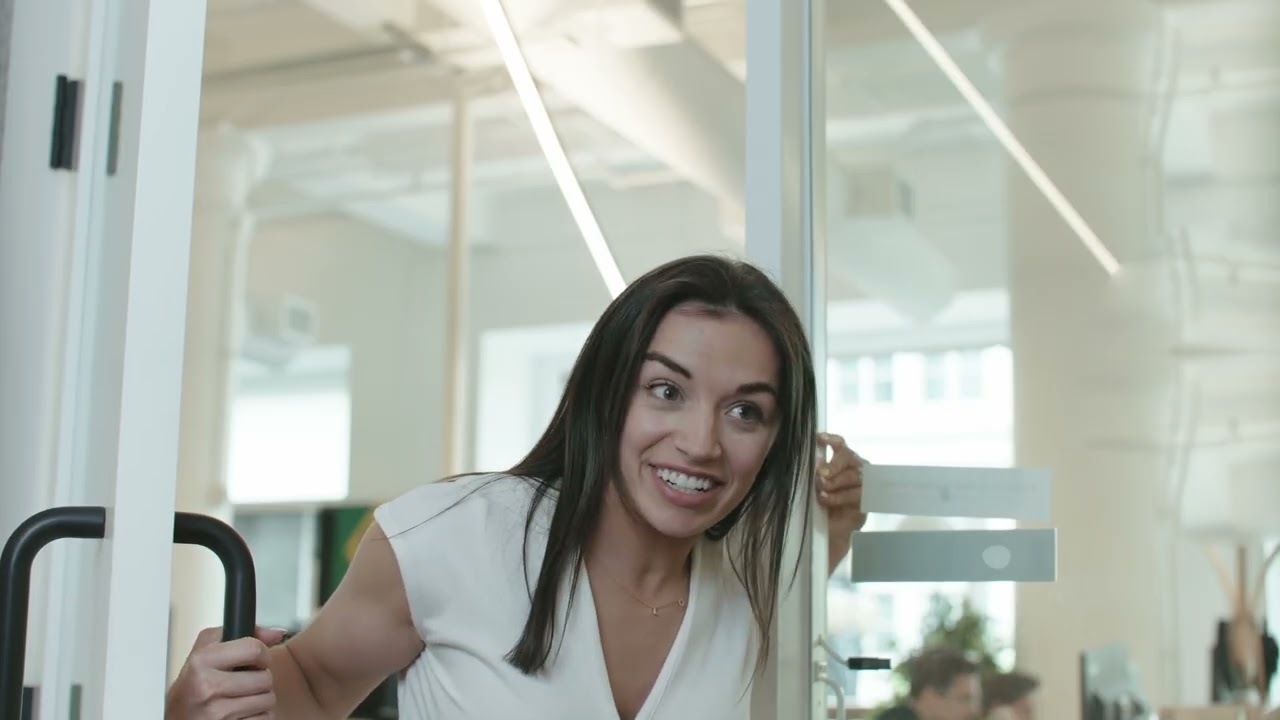 A woman leans through a glass office door.