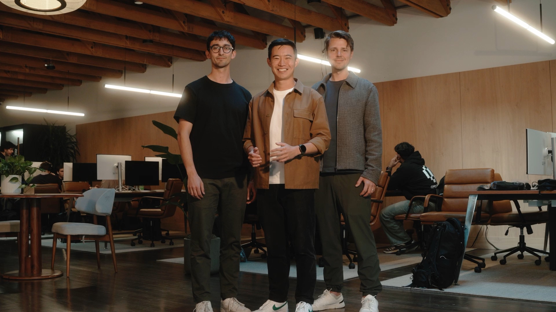 Three founders stand together in a sunlit office.