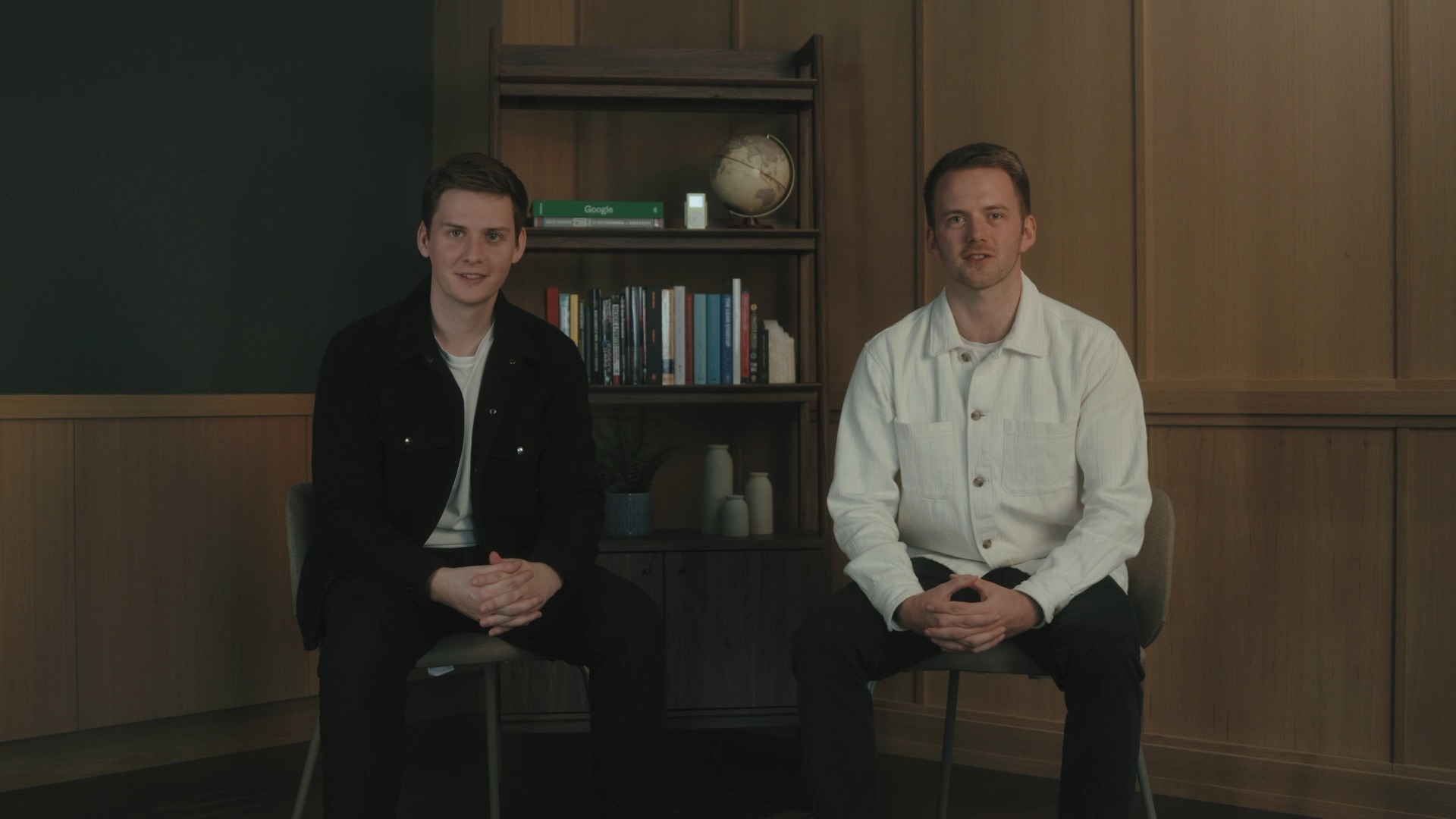 Two founders sit in a wood-paneled room.